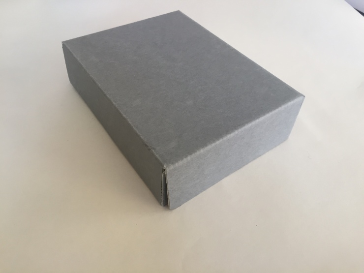 Image of a clamshell or drop spine box made from corrugated board, closed and flat on a surface